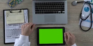 男医生正在用绿色屏幕的平板电脑查看病人的医疗记录