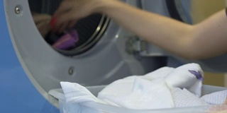 家务妇女小心翼翼地把脏衣服从篮子里放进洗衣机