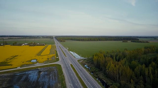高速公路在平原与森林和油菜田。无人机4K旋转拍摄。农作物产业物流