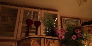 木制的圆木桌上放着两个酒杯。美丽的圣诞节冬季婚礼订婚仪式装饰蜡烛，桦木，灯泡花环和冷杉树枝。冬季结婚的概念