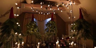 美丽的圣诞冬季婚礼拱门订婚装饰室内蜡烛，桦木，灯泡花环和冷杉树枝。冬季婚礼的概念。相机稳定剂