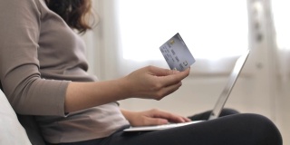 手持信用卡和笔记本电脑的年轻女子在网上购物