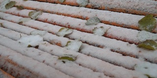 第一场白雪覆盖了公园里的橙色长凳。冬天多雪的寒冷天气。抽象背景与橙色线在雪。特写镜头