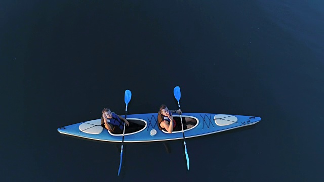 两个朋友玩皮划艇。漂浮在湖面上。从上面的观点