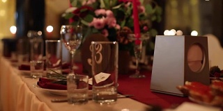圣诞婚礼宴会厅内部细节装饰和餐桌设置在餐厅。冬季装饰的球根花环，蜡烛，鲜花，球果和冷杉树枝