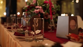 圣诞婚礼宴会厅内部细节装饰和餐桌设置在餐厅。冬季装饰的球根花环，蜡烛，鲜花，球果和冷杉树枝视频素材模板下载