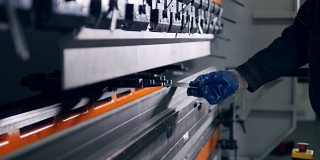 工人在工厂的现代弯曲工业机器上弯曲金属板。