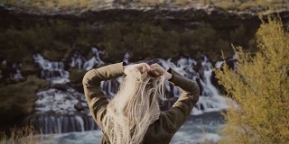 年轻的旅行女人的背影站在山谷和看瀑布在冰岛独自