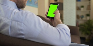 自信的男性用绿屏智能手机看政治新闻