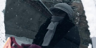 冬天，女人们手戴粉色手套清除汽车挡风玻璃上的积雪