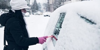 妇女清洁和准备汽车为困难的冬天在城市驾驶