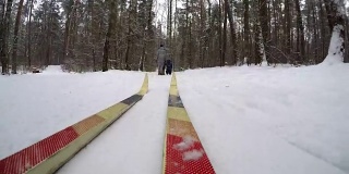 冬季健康生活理念。在下雪的冬天越野滑雪。越野滑雪的人会去圣诞森林。慢慢地下起了一场大雪。移动的摄像机安装在旧的越野滑雪板上。第一人称视角- POV