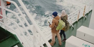 俯视图的年轻夫妇站在船上。男人和女人用动作相机享受大海的景色