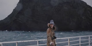 年轻漂亮的女人拿着相机站在船上环顾四周。高速摩托艇上的游客