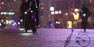 很多骑自行车的人在晚上骑自行车在模糊的自行车游行在灯光照亮城市街道的背景下，自行车timalapse的小比例模型。一群骑自行车的人。自行车交通。概念运动健康的生活方式。明亮的强光照射。低
