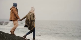 一对年轻的旅行情侣在海边散步。有魅力的男女在水边接吻