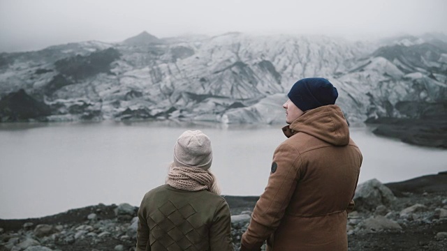 年轻夫妇站在冰礁湖的背影。一男一女一起探索冰岛