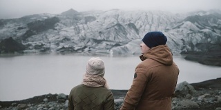 年轻夫妇站在冰礁湖的背影。一男一女一起探索冰岛