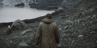 年轻男子独自走在冰湖上的背影。在冰岛冰川附近的火山中徒步旅行的男性