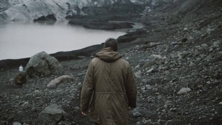 年轻男子独自走在冰湖上的背影。在冰岛冰川附近的火山中徒步旅行的男性视频素材模板下载
