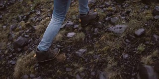 年轻女子徒步在岩石山的后视图。独自探索冰岛的旅行女性，徒步穿越沼泽