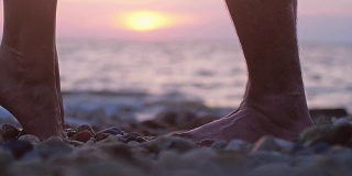 在美丽的日落时分，在海边的沙滩上，一对相爱的情侣在约会时的双腿。缓慢的运动。男人举起了手，举起心爱的女人。3840 x2160