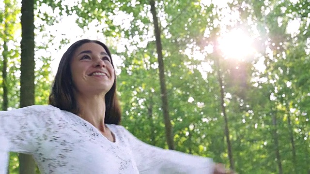 在一个阳光明媚的日子里，一名身穿白色连衣裙的女子手持彩色烟雾弹穿过田野，映衬着大自然的背景。观念生活方式，生态多彩，快乐人自由美妙