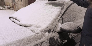 下雪天，女人用刷子刷着车