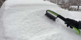 女人开始从被雪覆盖的汽车上清除积雪