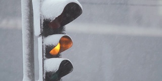 暴风雪期间，雪中的红绿灯控制交通。龙卷风来临时，大雪使道路上汽车的行驶变得复杂。特写镜头