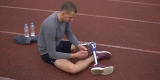 年轻的截肢运动员在赛道上使用手机