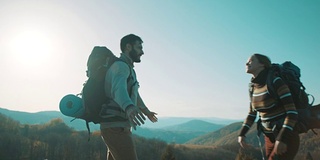 一男一女徒步旅行者在山顶拥抱并旋转