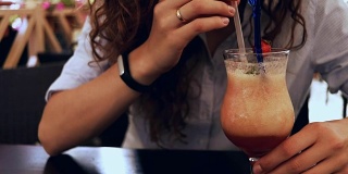 一个女人在咖啡馆喝鸡尾酒的特写镜头用吸管，慢动作