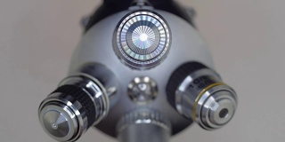 一只手转动着一块显微镜镜头，其中一个会发光