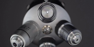 一只手转动着一块显微镜镜头，其中一个会发光