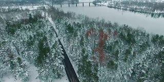 在冬季无人机拍摄的画面中，一辆汽车穿过积雪的松林