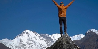 一个人爬上山顶，举起双手