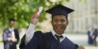 开朗的男毕业生向镜头展示证书，微笑着，成功了