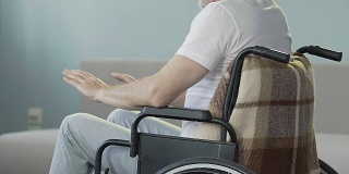 一位坐在轮椅上看着双腿点头的老人，失去了行走的能力