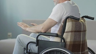 一位坐在轮椅上看着双腿点头的老人，失去了行走的能力视频素材模板下载