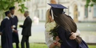 大学女毕业生等着朋友的到来，送花，拥抱
