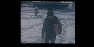 小男孩在暴风雪后在人行道上铲盐