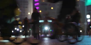 很多骑自行车的人在晚上骑自行车，自行车游行在模糊的灯光城市街道时间推移。一群骑自行车的人。自行车交通。概念运动健康的生活方式。明亮的强光照射。低角度的观点