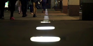 在昏暗的路灯下，辨认不出的人群在夜晚的城市中行走。周末的概念家庭之夜，拷贝空间