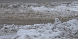路在雪中，在冬天下雪。龙卷风来临时，汽车在泥泞的道路上行驶。特写镜头