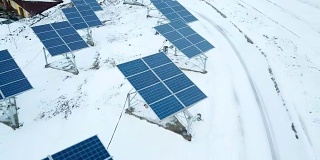 在小型太阳能发电厂，成排的积雪覆盖着太阳能电池板。