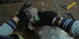 在车间使用角磨床打磨金属细部的工匠。