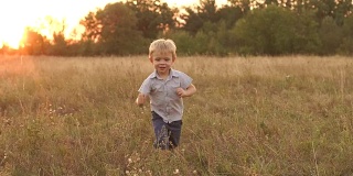 漂亮的小男孩在田野里奔跑。
