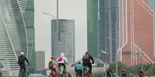 自行车城市赛事在摩天大楼的背景下竞争，成群的自行车手从成千上万的人骑自行车，在模糊中认不出的人，时间流逝