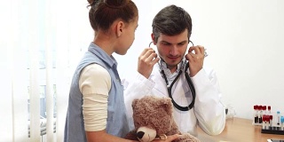 这位好医生正在用听诊器听小女孩的软玩具